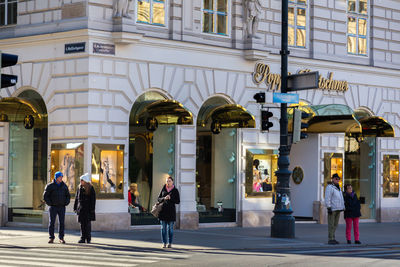 People walking on street against buildings in city