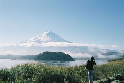 Rear view of two people standing on mountain against clear sky