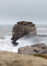 Rock formations on sea shore against sky