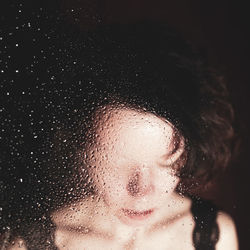 Close-up of woman seen through wet window