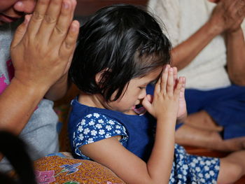 Family with hands clasped praying at home