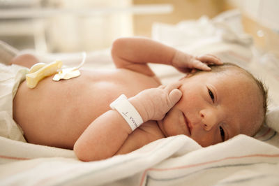 Close-up of newborn baby lying on hospital bed