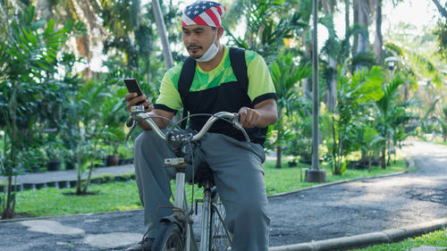 Full length of man riding bicycle on mobile phone