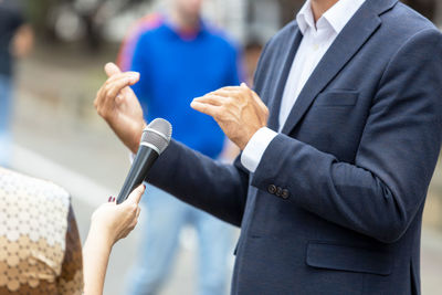 Midsection of man holding hands while standing outdoors