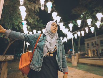 Woman standing by tree in city