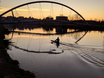 Silhouette man on bridge against sky during sunset