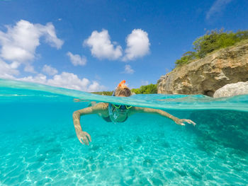 Rear view of woman swimming in sea against sky