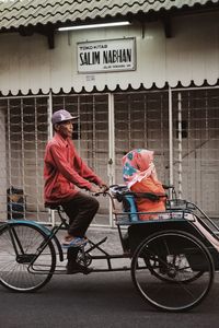 Rear view of people sitting on street in city