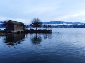 Scenic view of house on calm lake in winter