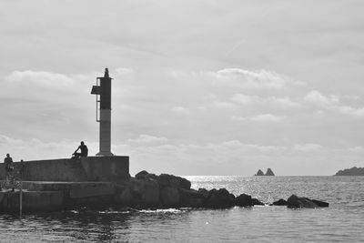 Lighthouse by sea against sky