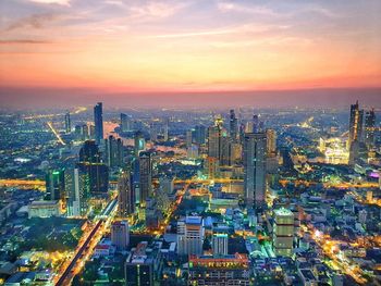 Aerial view of illuminated buildings in city against sky during sunset