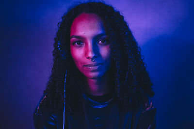 Portrait of serious young woman sitting against wall