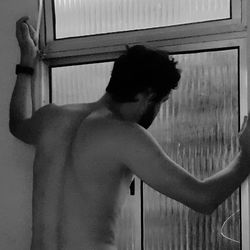 Rear view of shirtless man standing at home