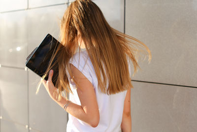 Rear view of woman standing against wall