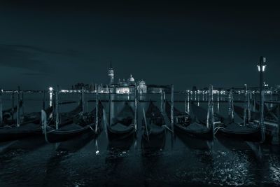 Boats moored in illuminated city at night