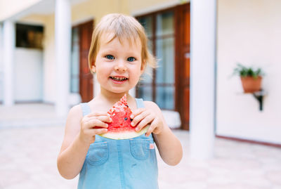 Little cute cheerful girl eating a slice of watermelon close up.