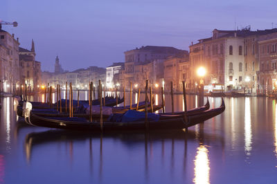 Gondolas moored on grand canal in city at night