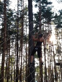 Low angle view of man standing by tree in forest