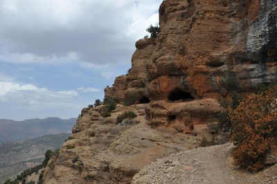 Low angle view of rock formations against cloudy sky