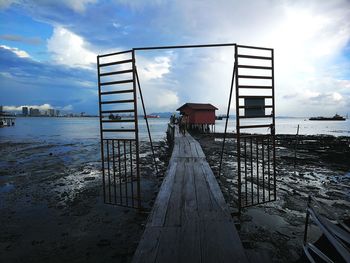 Pier on beach against sky