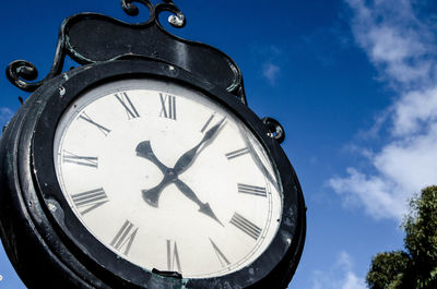 Low angle view of clock against sky