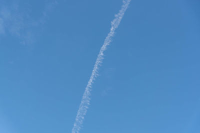 Low angle view of vapor trail against blue sky