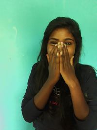 Portrait of beautiful young woman drinking against wall