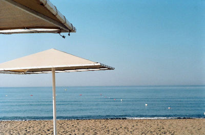 Lifeguard hut on beach against clear blue sky