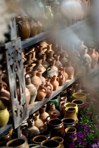 Many unique handmade colorful clay jugs and vases of various shapes on shelf in local market