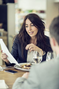 Businesswoman discussing with male colleague at restaurant table