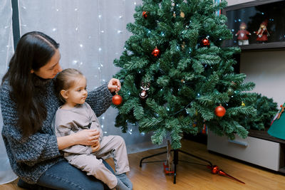 Side view of woman decorating christmas tree