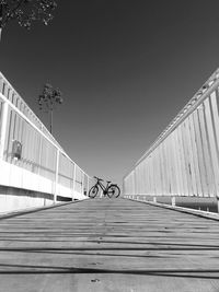 Bicycle on footbridge against clear sky