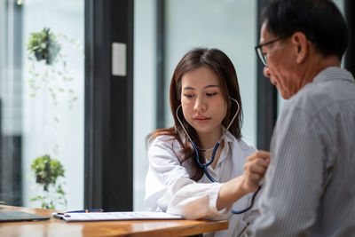 Smiling female doctor examining patient at home