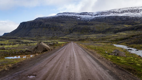 Road leading towards mountain against sky