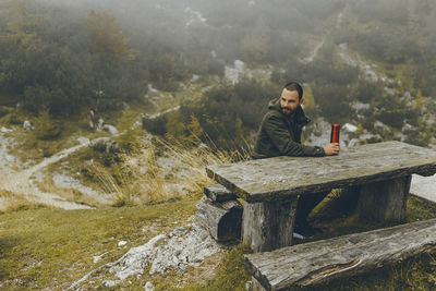 Young man sitting at table against landscape