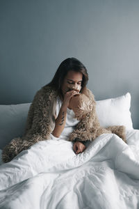 Young woman breathing in paper bag on bed at home