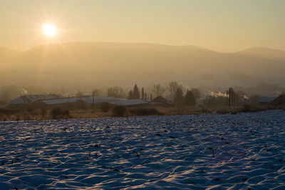 Frozen lake against sky during sunset
