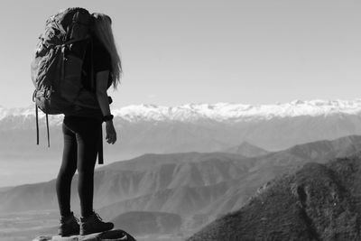 Rear view of woman standing on mountain against sky