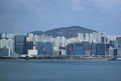 Sea and buildings against in city against sky