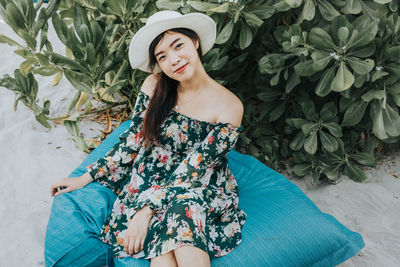 Portrait of smiling woman wearing hat sitting at beach