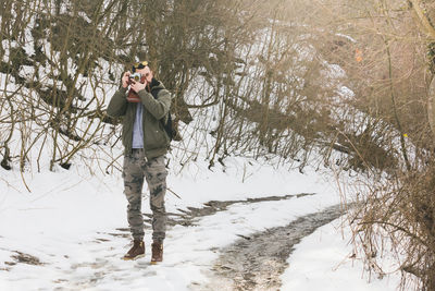 Man standing on snow covered tree