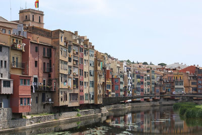 Buildings by river in town against sky