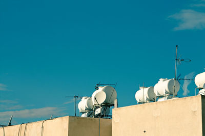 Low angle water tanks on rooftop against blue sky
