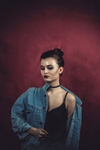 Beautiful young woman standing against red background