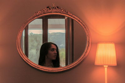 Portrait of woman looking through window at home