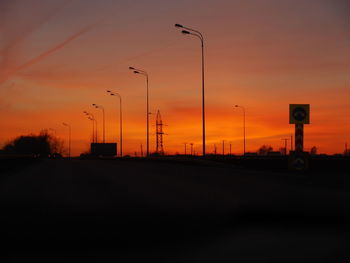 Street lights against orange sky