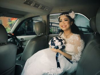 Smiling bride sitting in car
