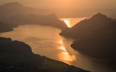 Scenic view of silhouette mountains and lake against sky during sunset