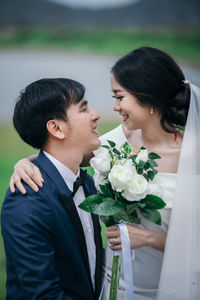 Couple holding bouquet against lake