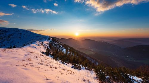 Scenic view of snow covered mountains against sky during sunset